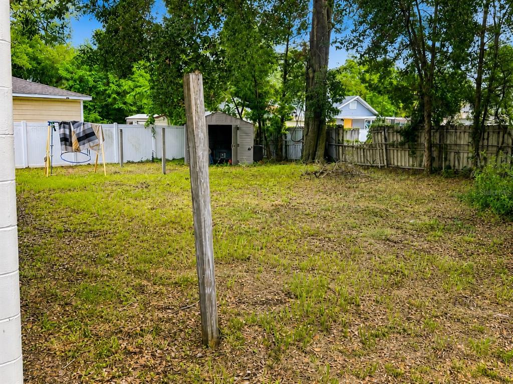 A backyard features a wooden post, a small shed, and a white vinyl fence — 712 N CASTLE COURT, TAMPA, FL