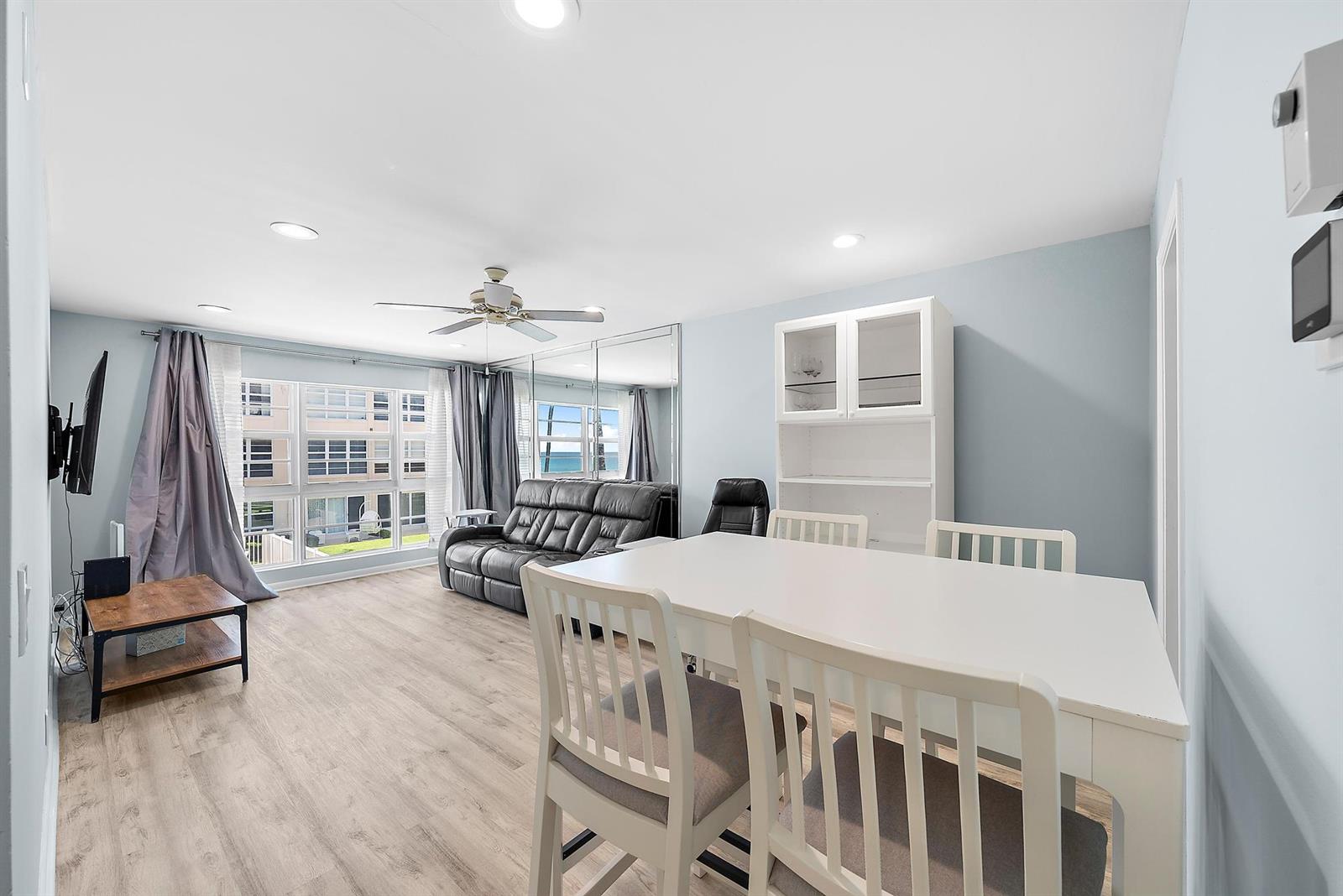 A dining and living area features light wood flooring, a white table, and mirrored walls — 3851 N Ocean Boulevard # 202, Gulf Stream FL 33483, GULF STREAM, FL