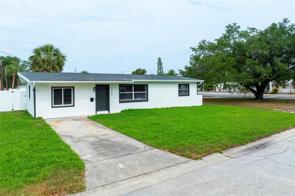 A single-story white house with a dark door and gray trim sits on a lawn — 3730 75TH STREET N, ST PETERSBURG, FL