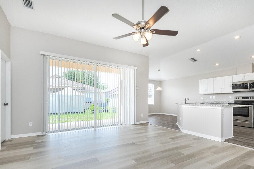 An open-concept living room and kitchen with light wood-look flooring and a ceiling fan — 1221 BARCLAY WOOD DRIVE, RUSKIN, FL