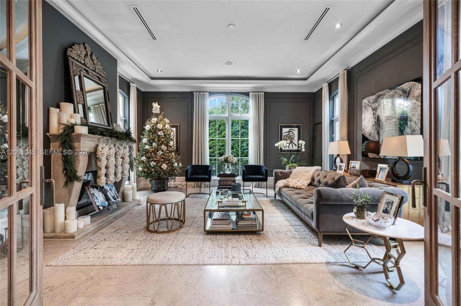 A formal living room features dark gray walls, a stone fireplace, and a tufted sofa — 9741 W Suburban Dr, Pinecrest FL 33156, PINECREST, FL