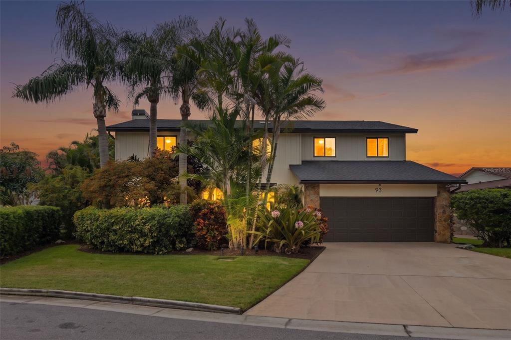 A two-story house with a garage, palm trees, and landscaping at sunset — 93 S CANAL DRIVE, PALM HARBOR, FL