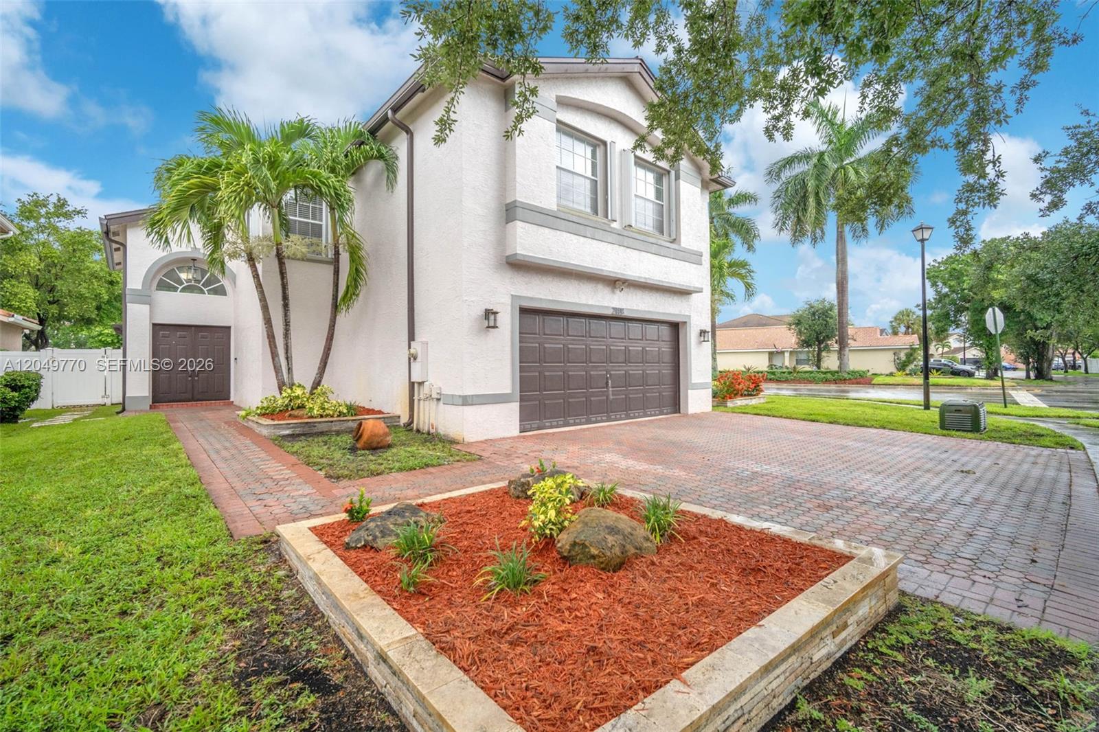 A two-story house with a brick driveway, a front garden bed, and palm trees — 2108 SW 151st Ave, Miramar FL 33027, MIRAMAR, FL