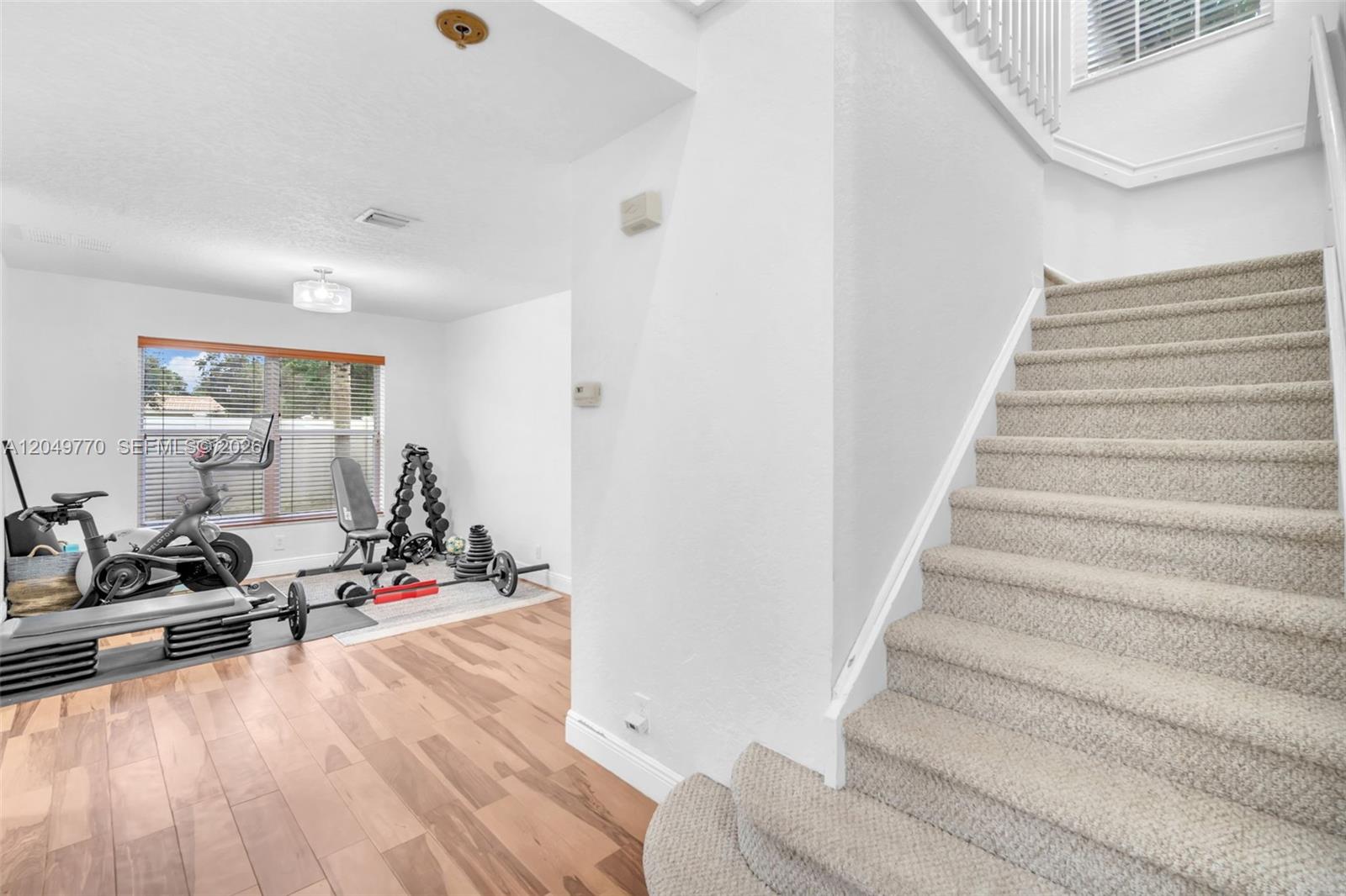 A home gym with exercise equipment sits next to a carpeted staircase in a house — 2108 SW 151st Ave, Miramar FL 33027, MIRAMAR, FL