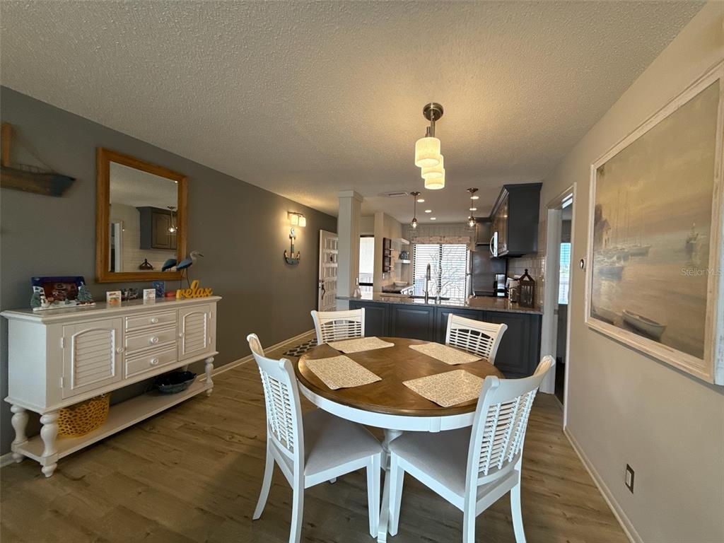 A dining room with a round wooden table, white chairs, and a white sideboard — 6158 PALMA DEL MAR BOULEVARD S UNIT 205, ST PETERSBURG, FL