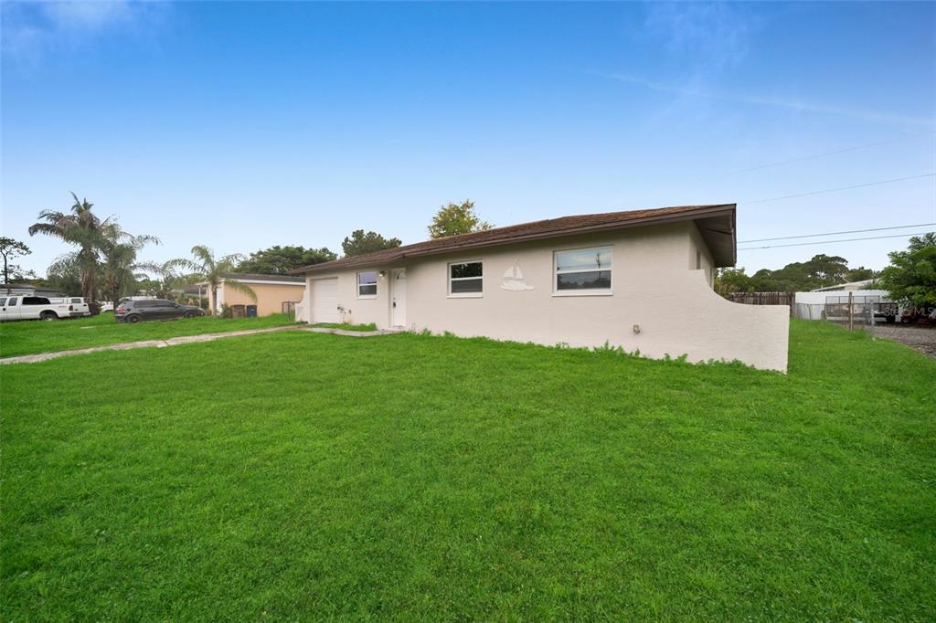 A single-story house with a beige exterior, a brown roof, and a large front lawn — 38 ABACO STREET, LEHIGH ACRES, FL
