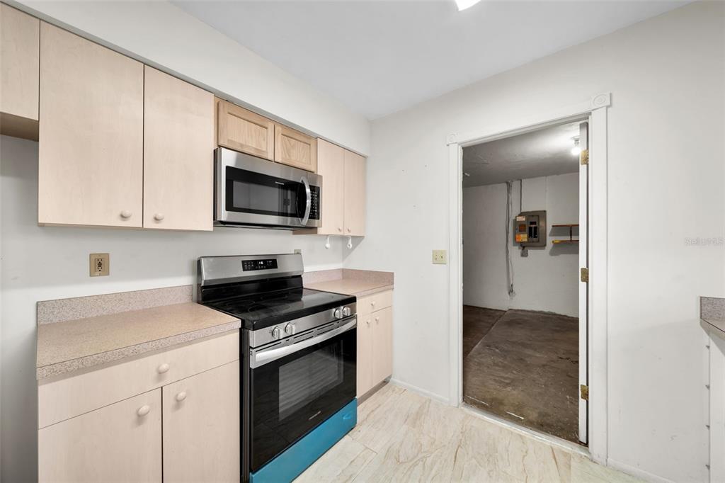 A kitchen features light wood cabinets, stainless steel appliances, and a doorway leading to a utility room — 38 ABACO STREET, LEHIGH ACRES, FL