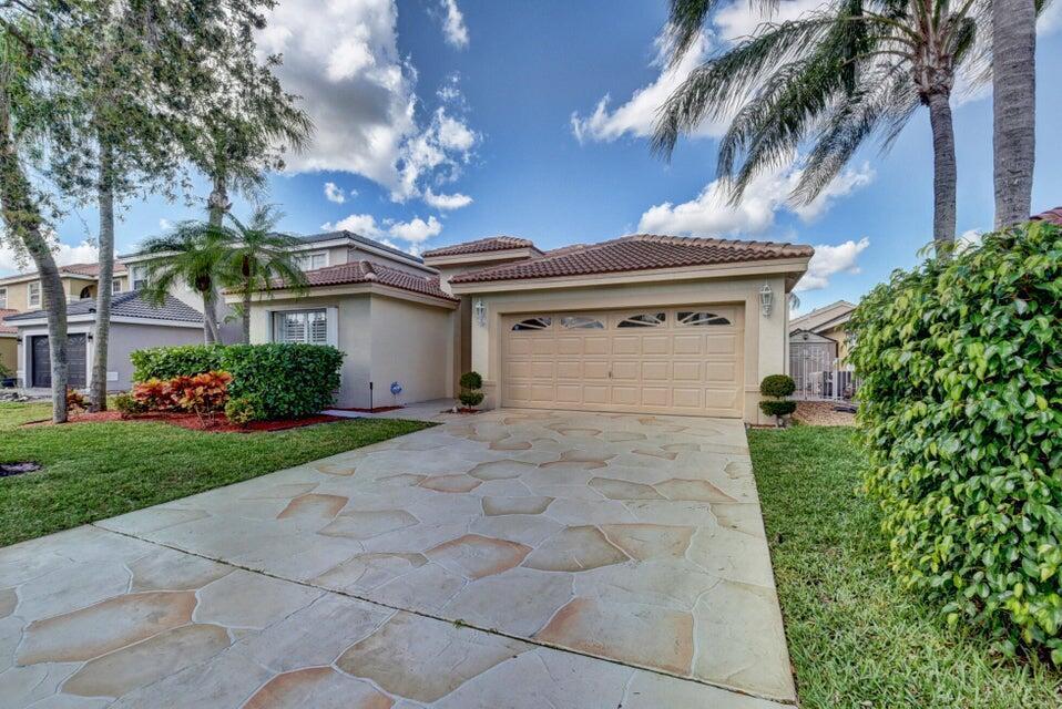 A beige house with a stone-patterned driveway, a two-car garage, and palm trees — 18967 Treble Lane, Boca Raton FL 33498, BOCA RATON, FL