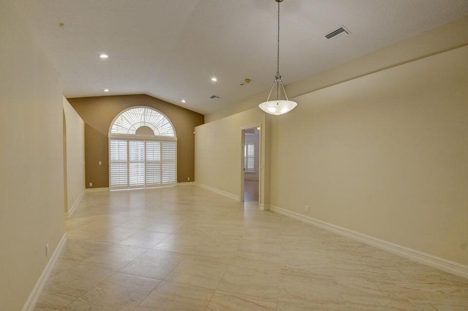 An empty room with light-colored tile flooring, a vaulted ceiling, and a large arched window — 18967 Treble Lane, Boca Raton FL 33498, BOCA RATON, FL