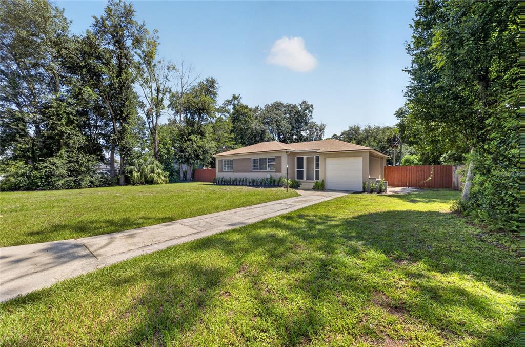 A single-story house with a tan exterior, a white garage door, and a concrete driveway — 2403 KEY AVENUE, SANFORD, FL