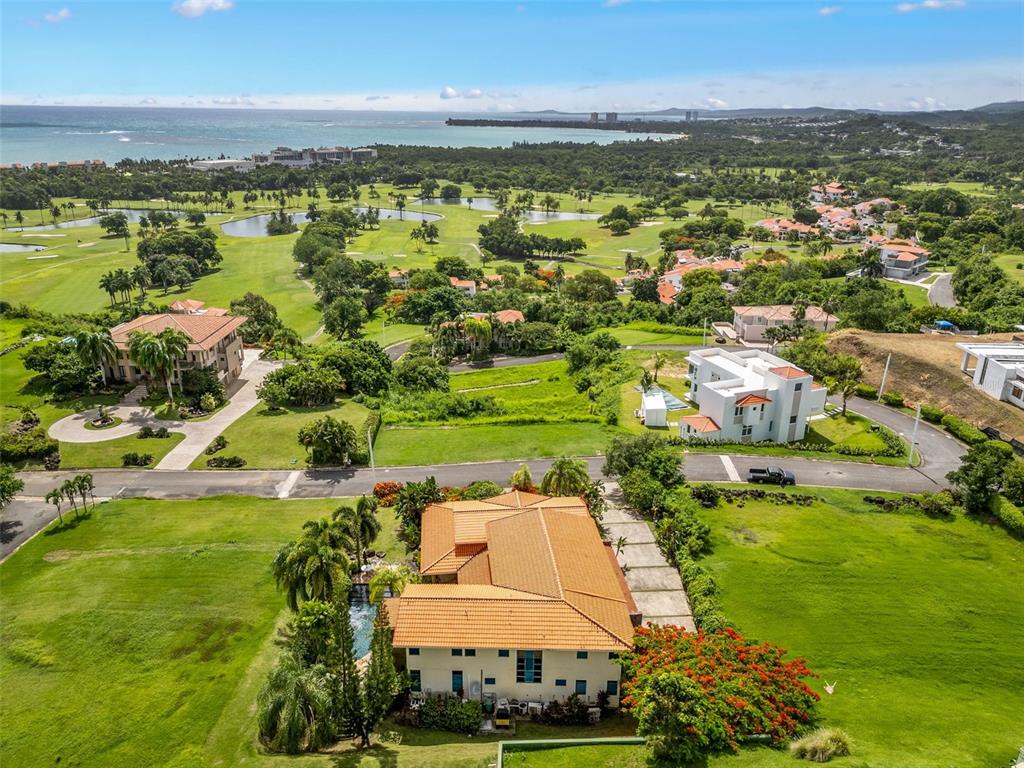 An aerial view of a house with a terracotta roof overlooking a golf course and ocean — 13 MIRADOR NE UNIT 13, RIO GRANDE, PR