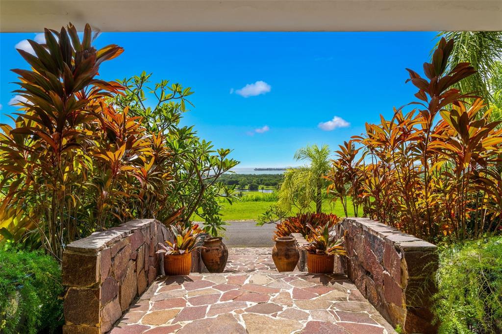 A stone walkway leads through lush tropical plants toward a scenic view of the ocean — 13 MIRADOR NE UNIT 13, RIO GRANDE, PR