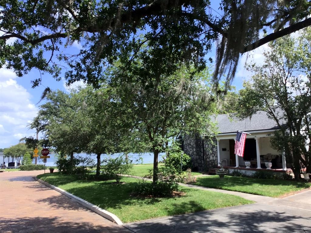 A stone-faced house with a front porch and American flag sits near a lake — 120 BROADVIEW AVENUE, WINTER PARK, FL