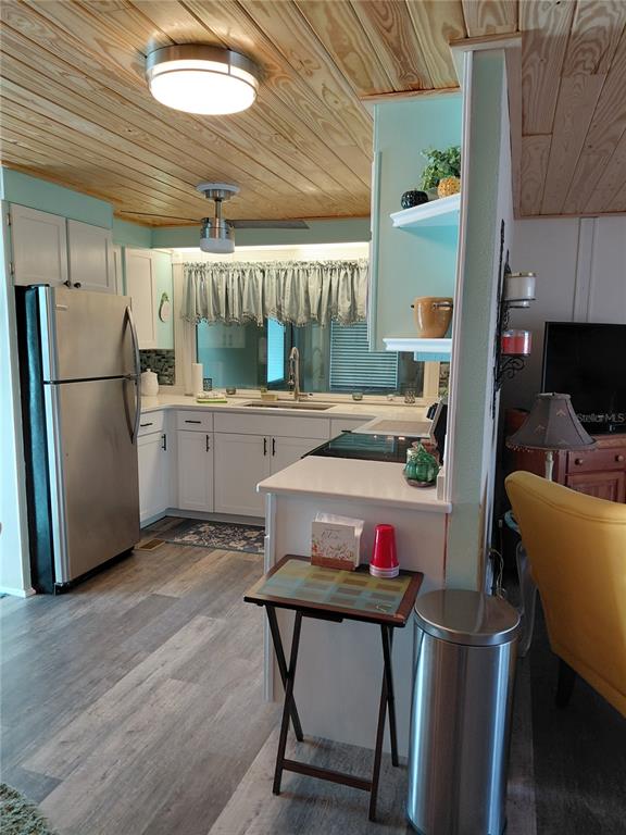 A kitchen features white cabinets, stainless steel appliances, and a wood-paneled ceiling — 1451 BLUE HERON DRIVE, ENGLEWOOD, FL
