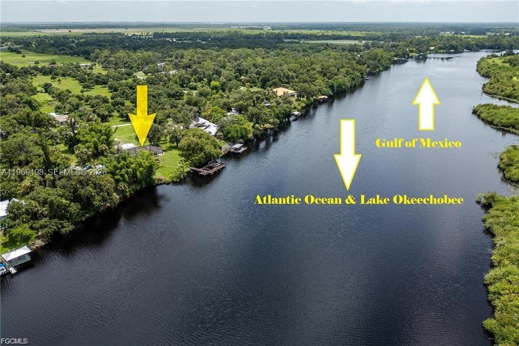 An aerial view shows a house on a riverbank with arrows pointing toward bodies of water — 2030 Ft Denaud Rd, La Belle FL 33935, LA BELLE, FL