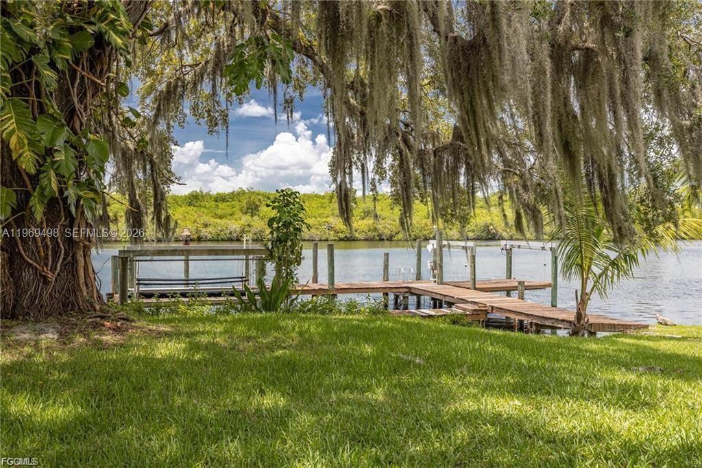 A wooden dock extends into a calm river under large trees draped with Spanish moss — 2030 Ft Denaud Rd, La Belle FL 33935, LA BELLE, FL