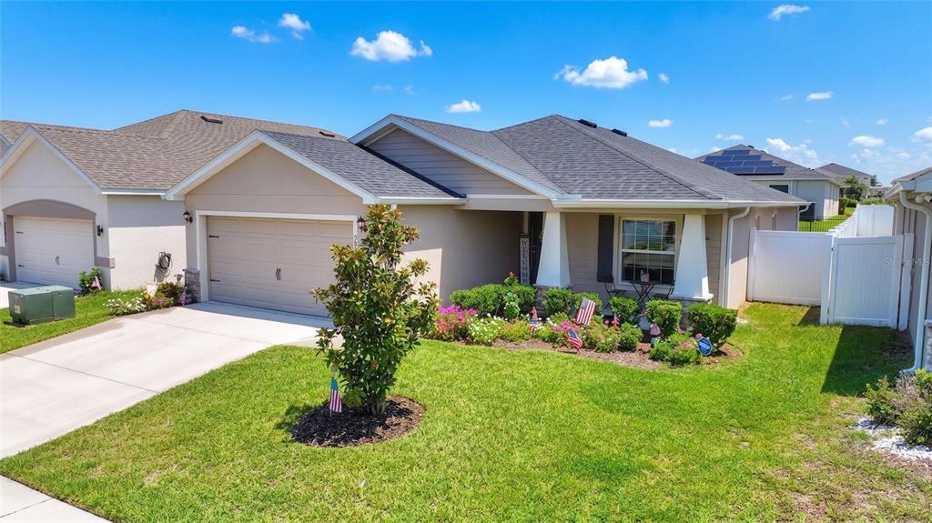 A single-story suburban house with a two-car garage, landscaped front yard, and white vinyl fencing — 2295 SUNSET WAY, DAVENPORT, FL