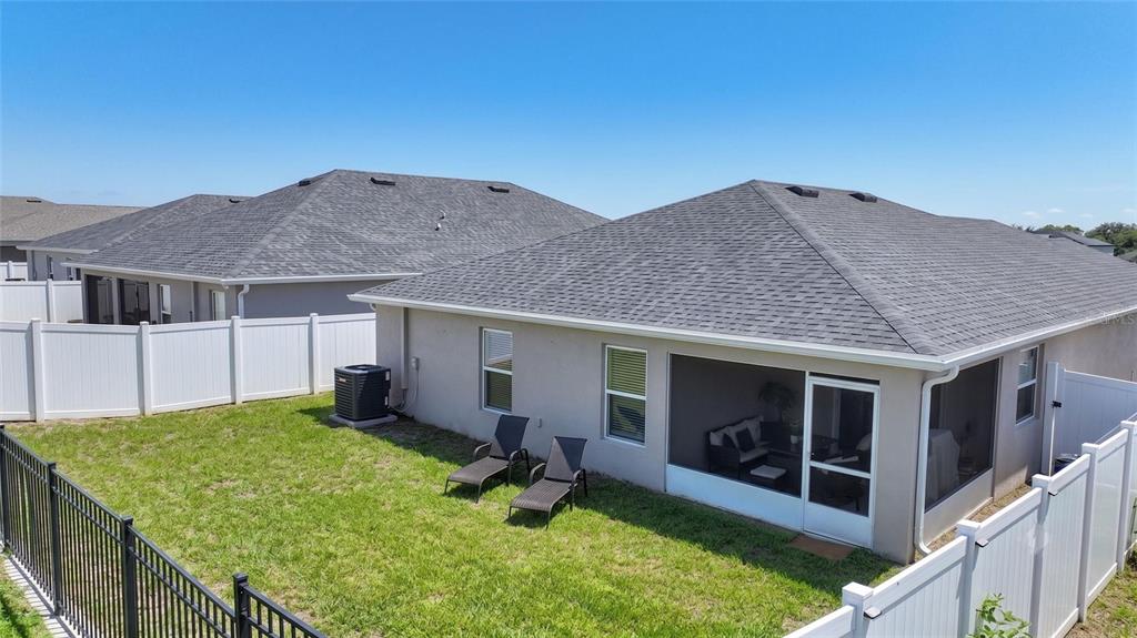 A backyard with a screened-in patio, two lounge chairs, and white vinyl privacy fencing — 2295 SUNSET WAY, DAVENPORT, FL