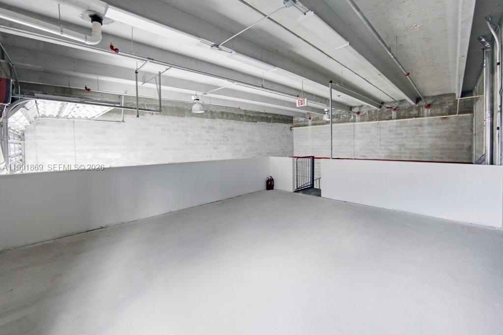 This industrial-style space features concrete block walls, exposed ceiling beams, and a metal staircase — 2355 NW 70th Ave # 3, Miami FL 33122, MIAMI, FL