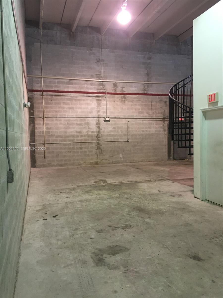 An industrial interior space features concrete block walls, a concrete floor, and a spiral staircase — 2355 NW 70th Ave # 3, Miami FL 33122, MIAMI, FL