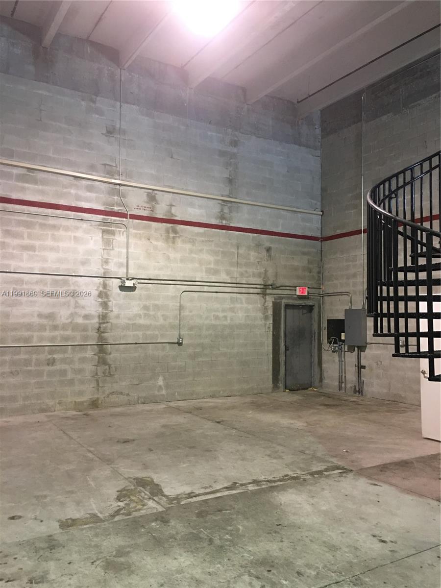 An industrial space features concrete block walls, a concrete floor, and a black spiral staircase — 2355 NW 70th Ave # 3, Miami FL 33122, MIAMI, FL