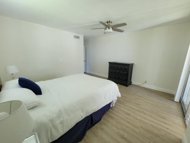 A bedroom features light wood-look flooring, a ceiling fan, and a dark wooden dresser — 6650 S Oriole Boulevard # 4080, Delray Beach FL 33446, DELRAY BEACH, FL