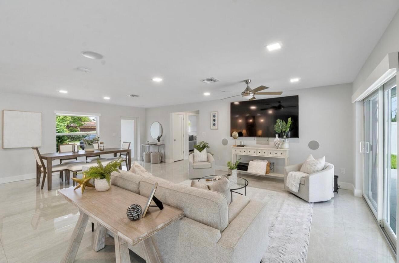 A bright, open-concept living and dining area features light tile flooring and a large television — 2846 NE 35th Court, Lighthouse Point FL 33064, LIGHTHOUSE POINT, FL