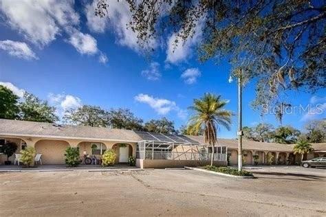 A single-story building with arched entryways and a screened-in patio area under a blue sky — 4390 SIBLEY BAY STREET UNIT J-D, PUNTA GORDA, FL