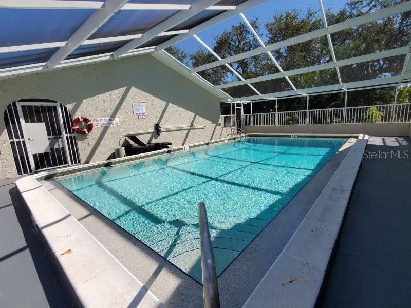 An indoor swimming pool with a screened enclosure and a white safety railing — 4390 SIBLEY BAY STREET UNIT J-D, PUNTA GORDA, FL