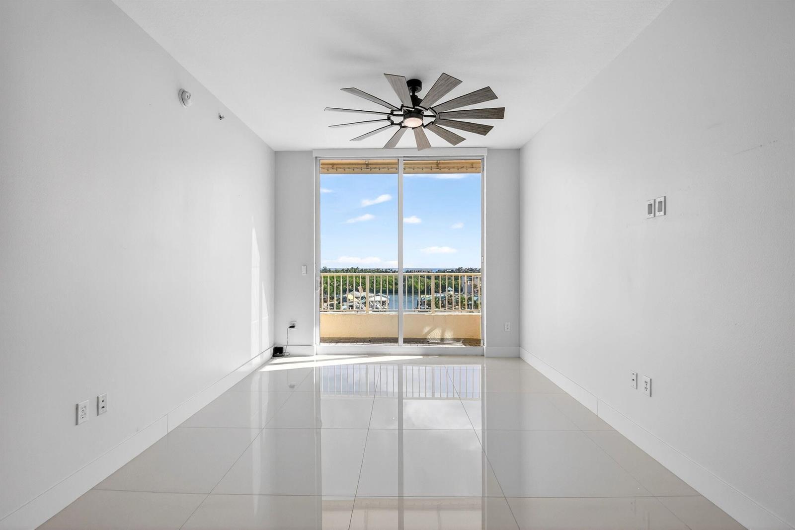 An empty room with white walls, glossy tile floors, a ceiling fan, and a balcony view — 100 NE 6th Street # 704, Boynton Beach FL 33435, BOYNTON BEACH, FL