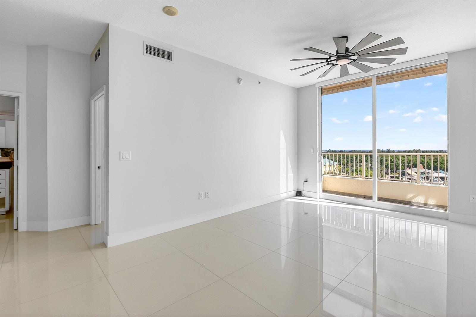 An empty room with white walls, glossy tile floors, a ceiling fan, and a balcony — 100 NE 6th Street # 704, Boynton Beach FL 33435, BOYNTON BEACH, FL