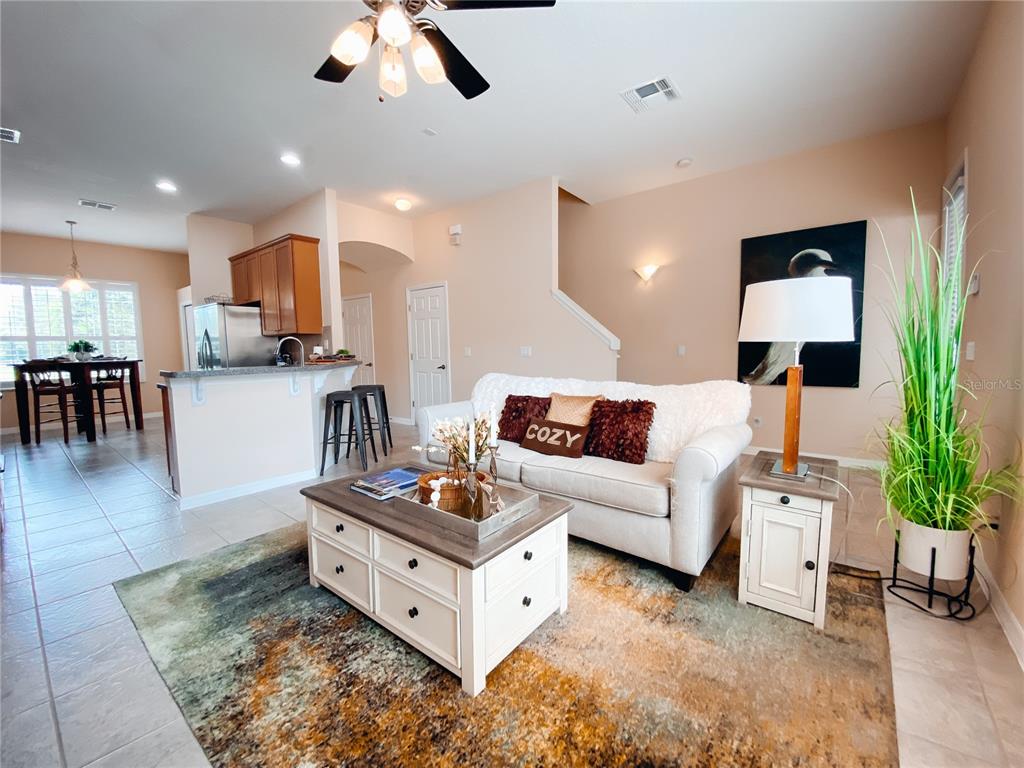 A living room with a white sofa, coffee table, and area rug opens to a kitchen — 612 ROGUE DRIVE, LONGWOOD, FL