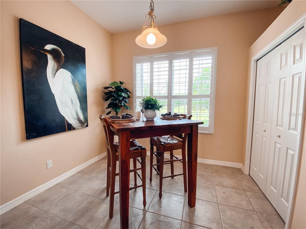 A dining area features a wooden table, two bar stools, and a large bird painting — 612 ROGUE DRIVE, LONGWOOD, FL