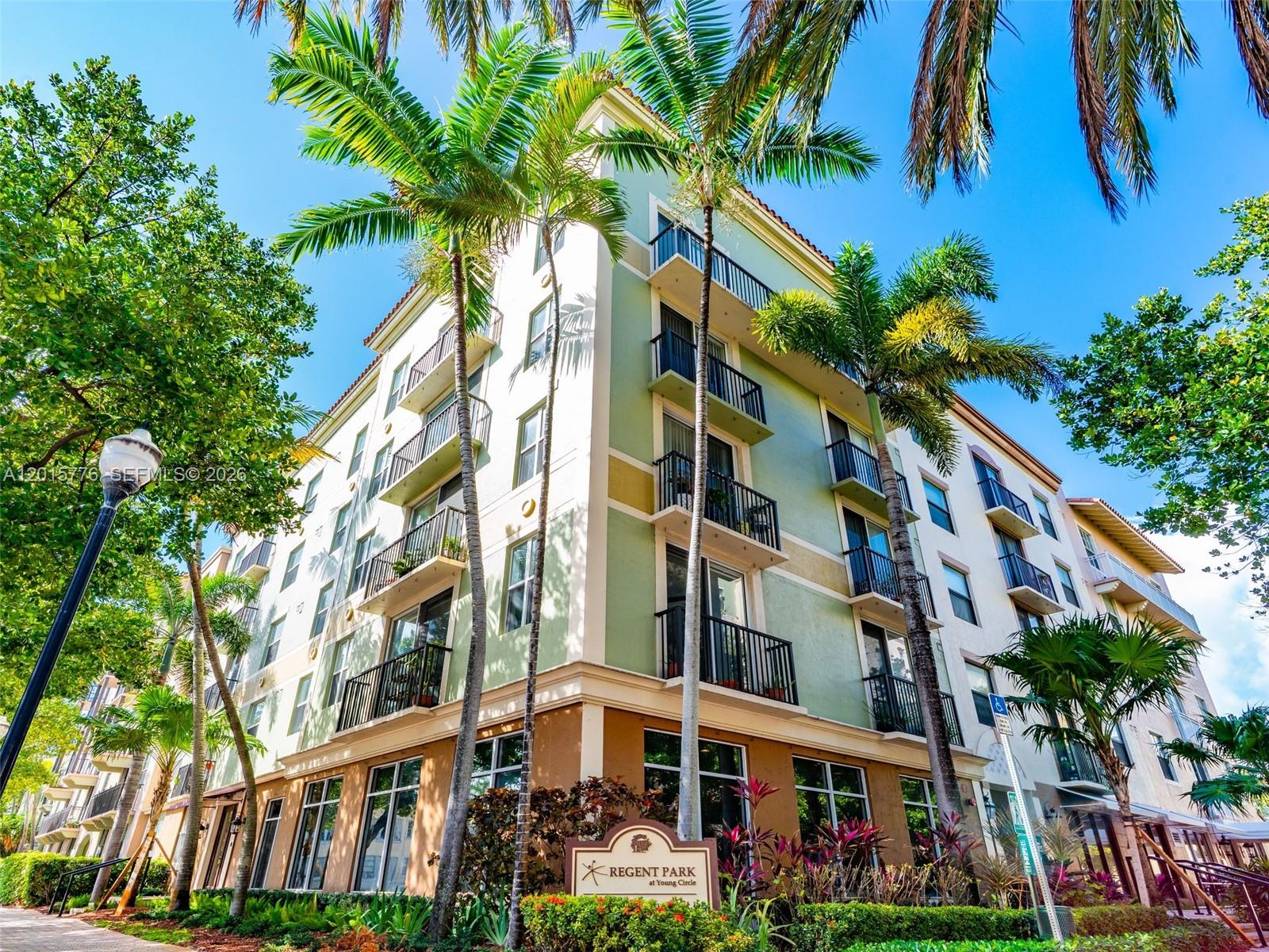 A low-angle exterior view of a multi-story apartment building with balconies and palm trees — 1900 Van Buren St # 112B, Hollywood FL 33020, HOLLYWOOD, FL