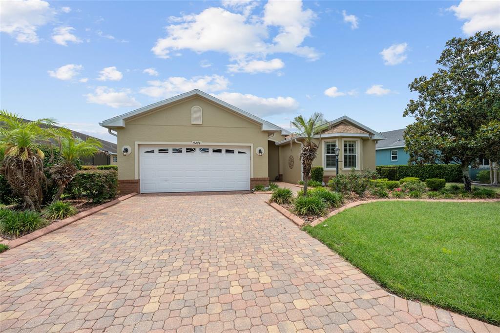A single-story house with a white garage door and a paved driveway under a blue sky — 9274 SW 94TH LOOP, OCALA, FL