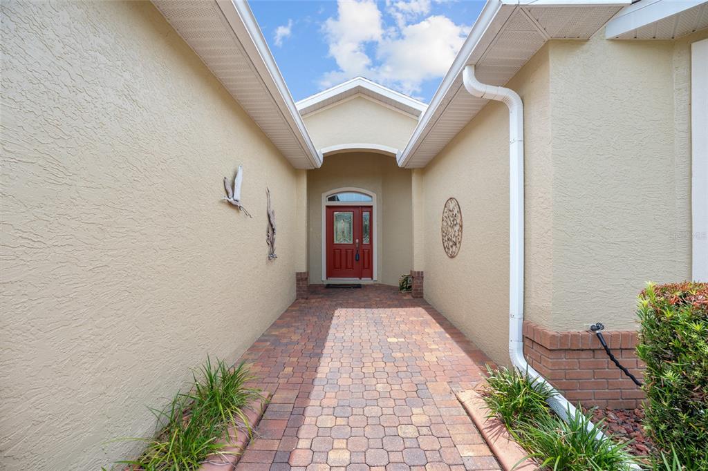 A paved walkway leads to a red front door set in a recessed entryway — 9274 SW 94TH LOOP, OCALA, FL