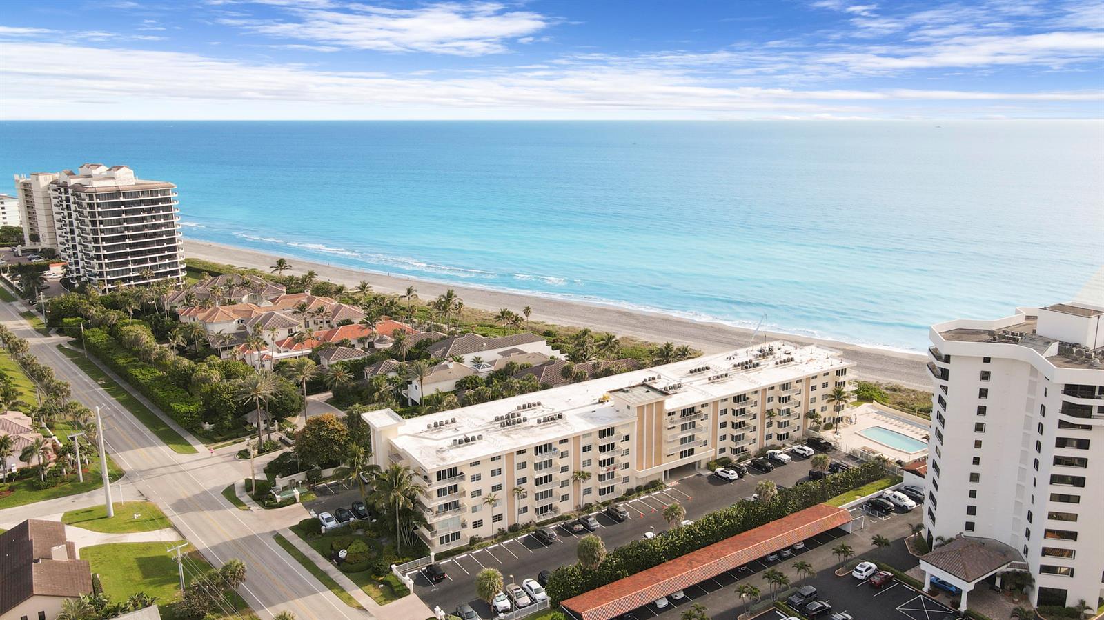 An aerial view shows beachfront condominiums, a parking lot, and a road along the coast — 630 Ocean Drive # 102, Juno Beach FL 33408, JUNO BEACH, FL