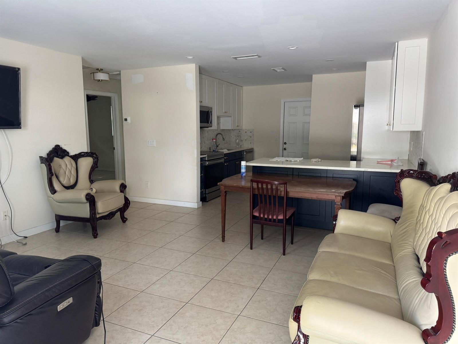 An open-concept living room and kitchen featuring tile floors, dark cabinetry, and traditional furniture — 1869 Windsor Drive # 1869, North Palm Beach FL 33408, NORTH PALM BEACH, FL