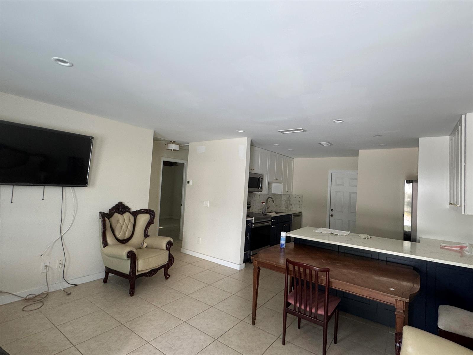 An open-concept living area features a kitchen with dark cabinets, a dining table, and tile flooring — 1869 Windsor Drive # 1869, North Palm Beach FL 33408, NORTH PALM BEACH, FL