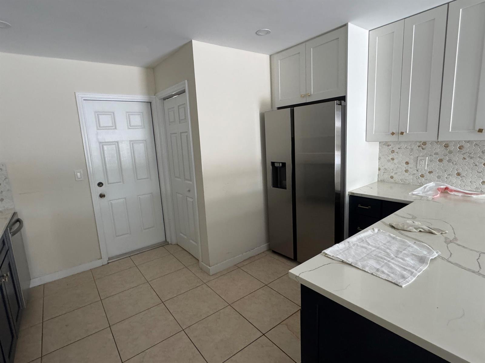 A kitchen features white cabinets, a stainless steel refrigerator, and a white quartz countertop — 1869 Windsor Drive # 1869, North Palm Beach FL 33408, NORTH PALM BEACH, FL