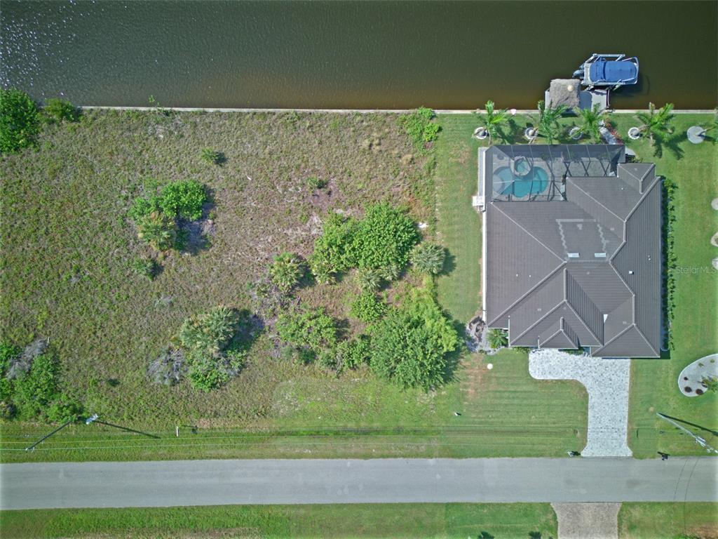 An aerial view shows a vacant waterfront lot next to a house with a pool — 15482 MEACHAM CIRCLE, PORT CHARLOTTE, FL