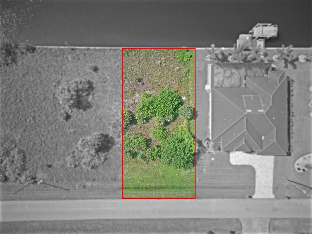 An aerial view shows a rectangular vacant lot outlined in red next to a house — 15482 MEACHAM CIRCLE, PORT CHARLOTTE, FL