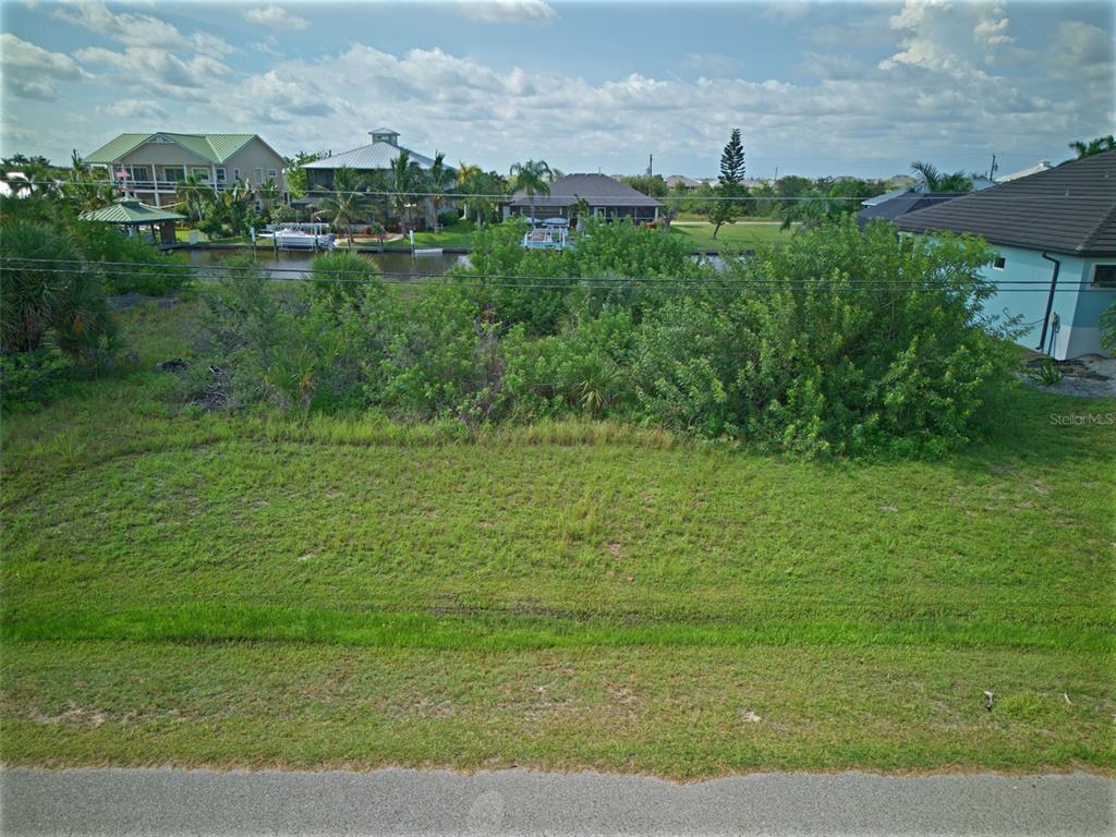 An elevated view of a grassy vacant lot overlooking a canal with houses beyond — 15482 MEACHAM CIRCLE, PORT CHARLOTTE, FL