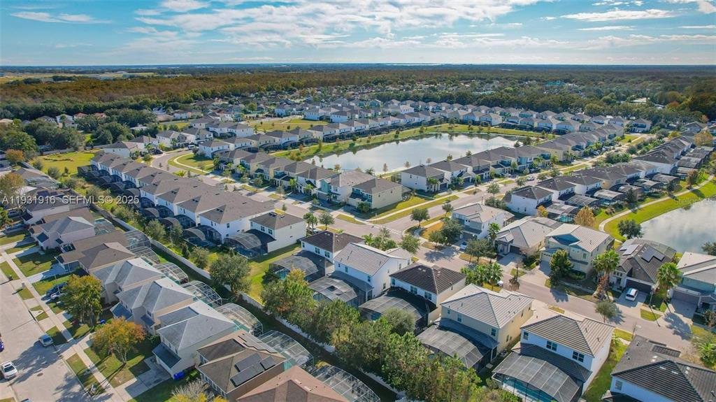 An aerial view shows a dense suburban neighborhood with numerous houses surrounding a central pond — 4503 MONADO DRIVE, KISSIMMEE, FL
