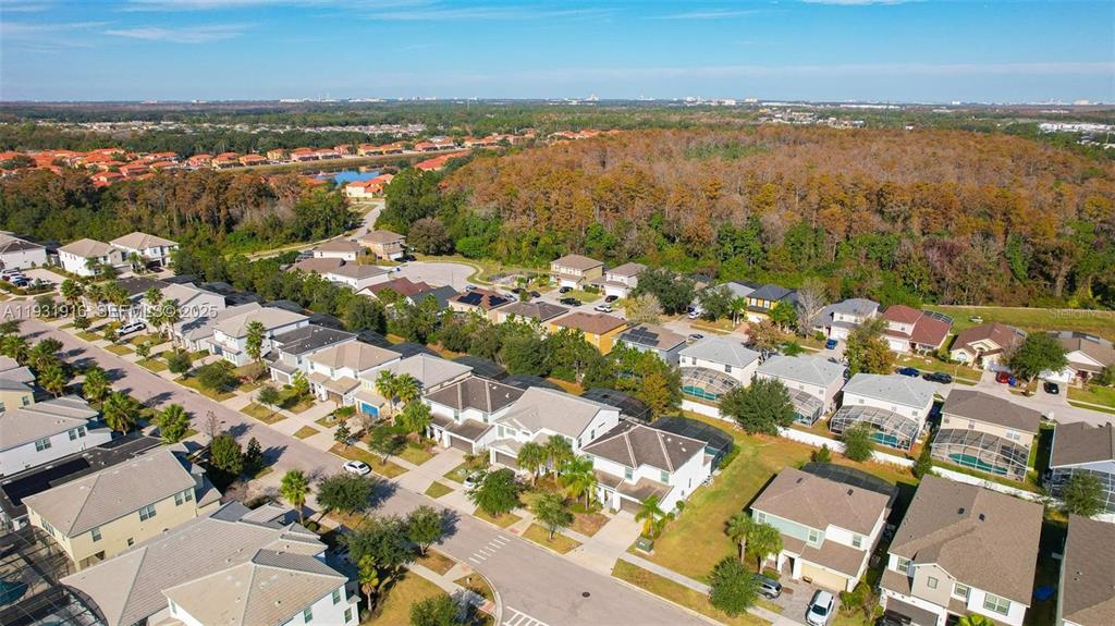 An aerial view shows a suburban neighborhood with houses, driveways, and surrounding wooded areas — 4503 MONADO DRIVE, KISSIMMEE, FL