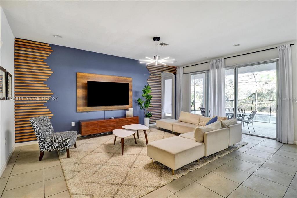 A living room features a blue accent wall with wood slats, a television, and sectional sofa — 4503 MONADO DRIVE, KISSIMMEE, FL