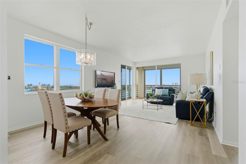 A bright, open-concept living and dining area features light wood floors and floor-to-ceiling windows — 7932 SAILBOAT KEY BOULEVARD S UNIT 701, SOUTH PASADENA, FL