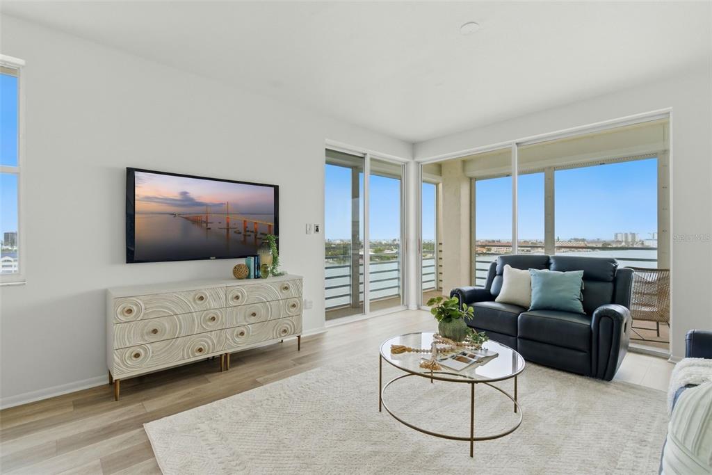 A living room features a white textured console, a dark sofa, and floor-to-ceiling windows — 7932 SAILBOAT KEY BOULEVARD S UNIT 701, SOUTH PASADENA, FL
