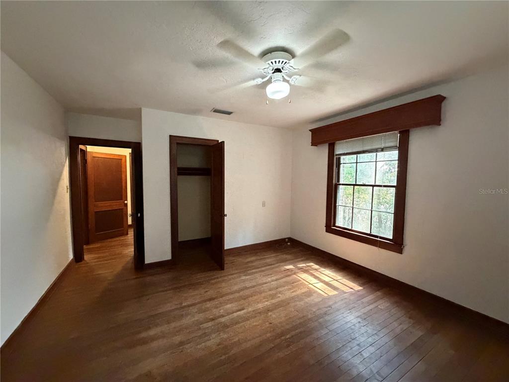 A bedroom with hardwood floors, a ceiling fan, a closet, and a window with trim — 1740 NW 7TH AVENUE, GAINESVILLE, FL