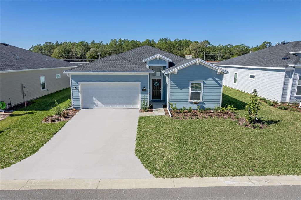 A blue, single-story suburban house with a two-car garage and a front lawn — 7931 SW 74TH LOOP, OCALA, FL